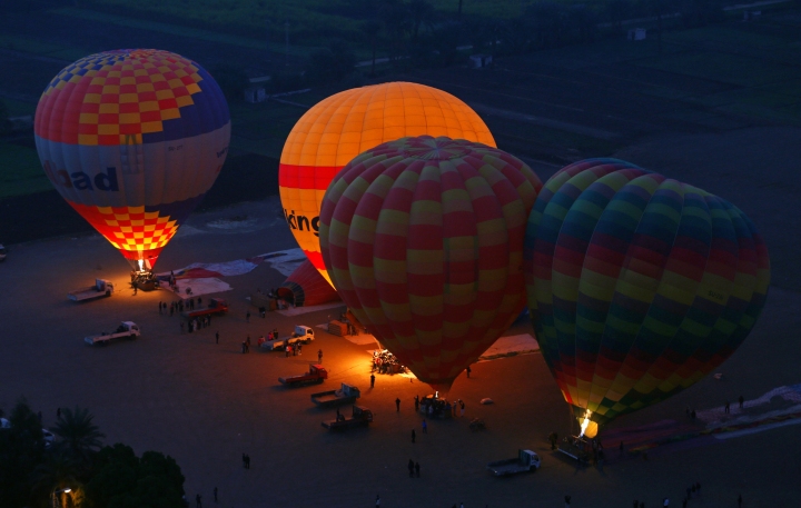 Hot air balloons carrying tourists take off before sunrise over the city of Luxor